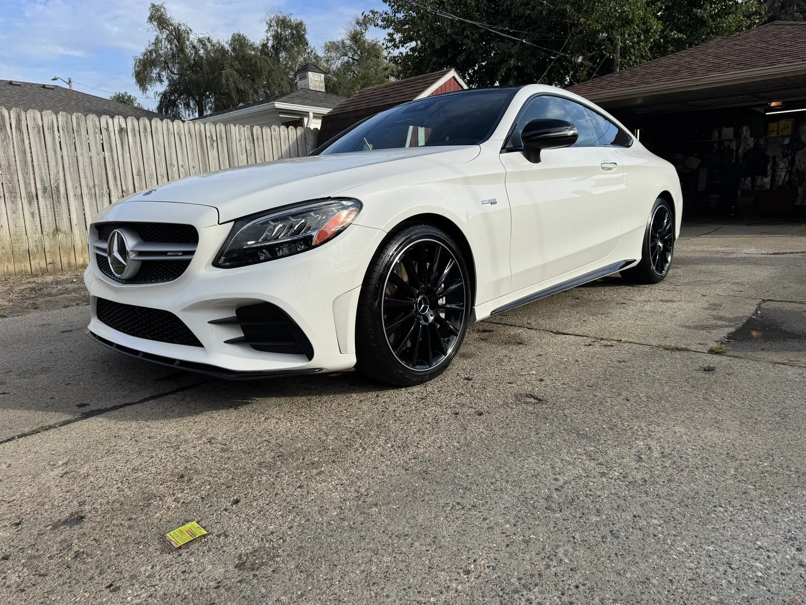 White Mercedes-AMG coupe photographed from the front corner in a driveway