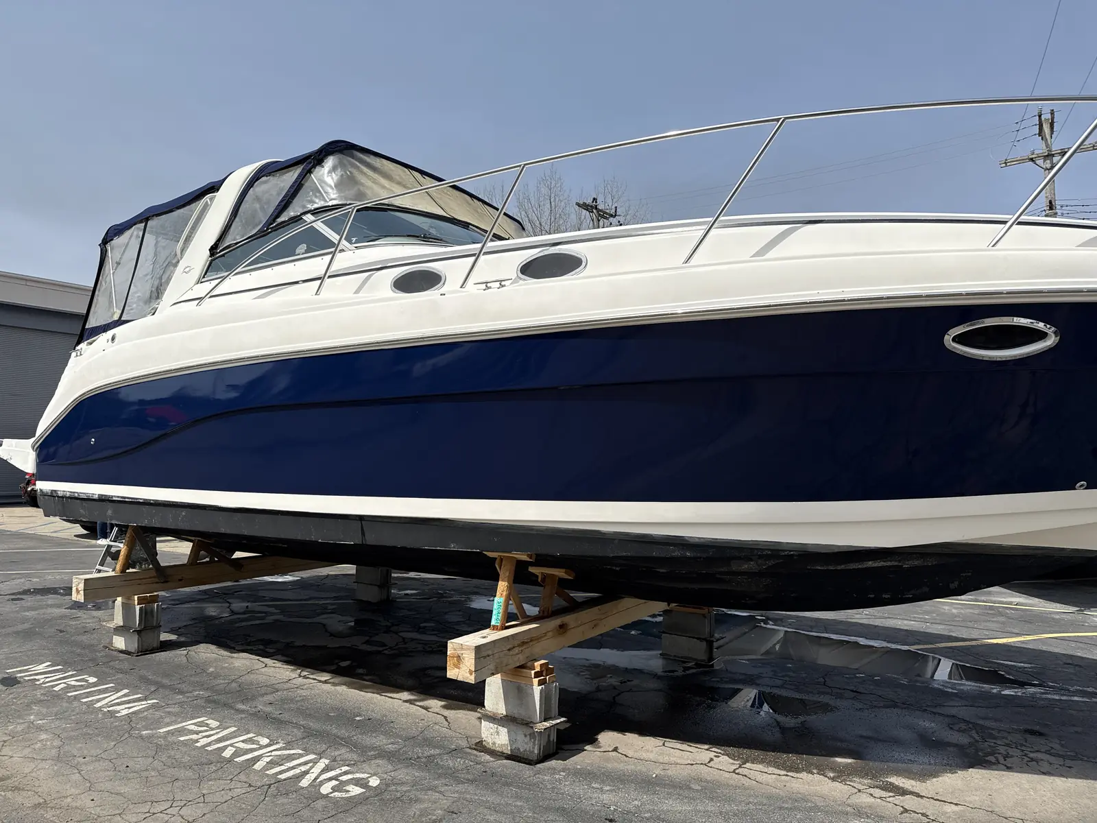 Navy and white cabin cruiser hull on blocks