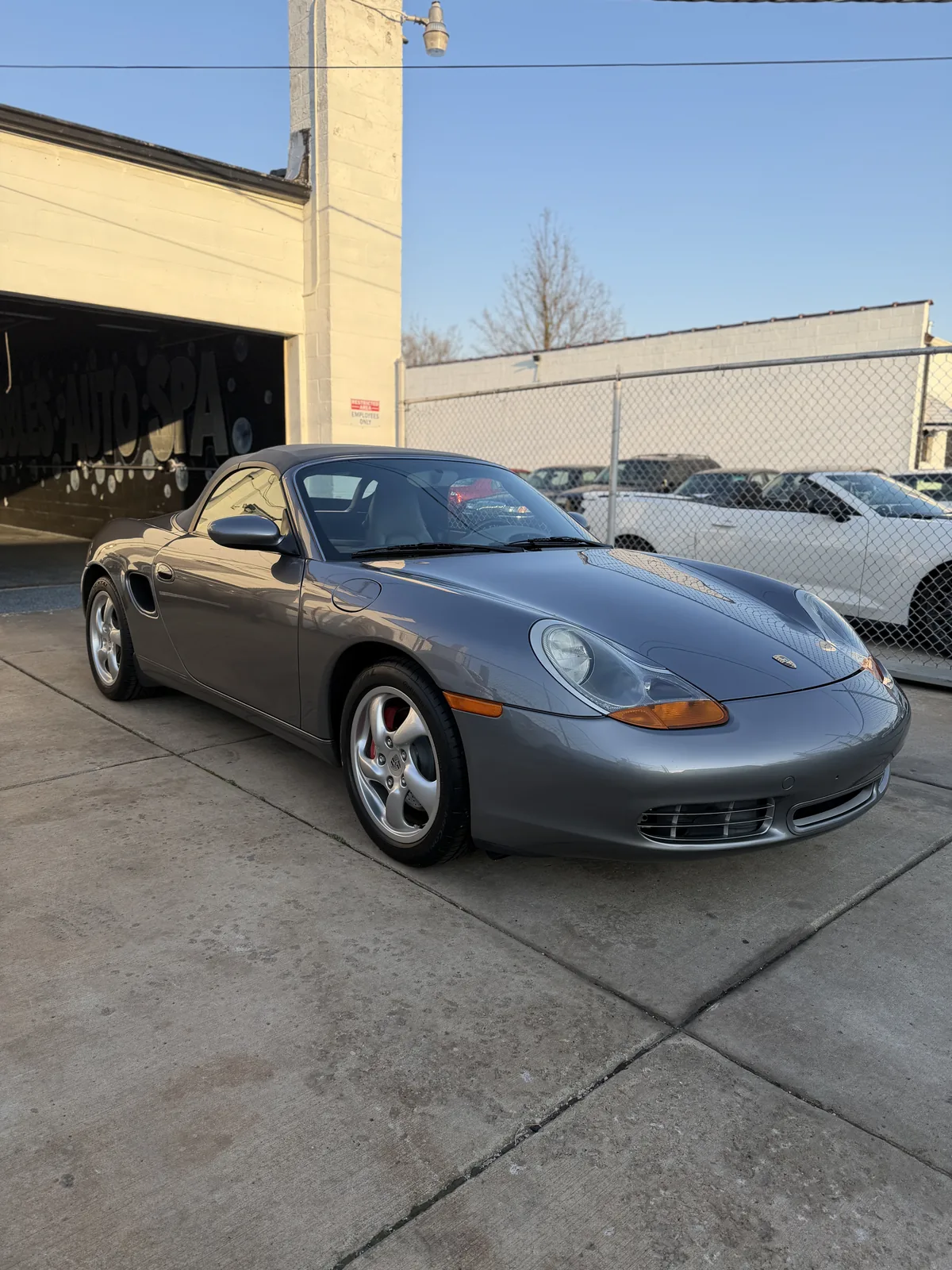 Grey Porsche Boxster outside the shop on a sunny day