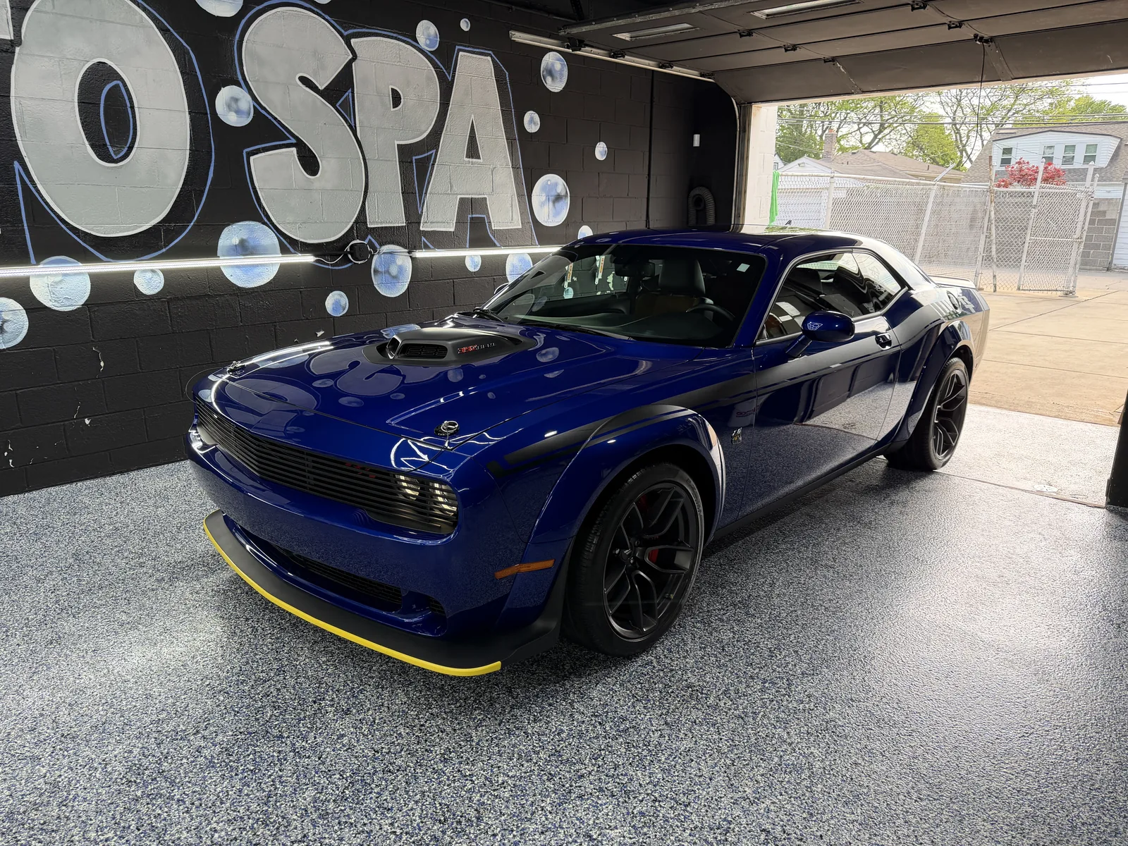 Blue Dodge Challenger in the studio with the door open to the street