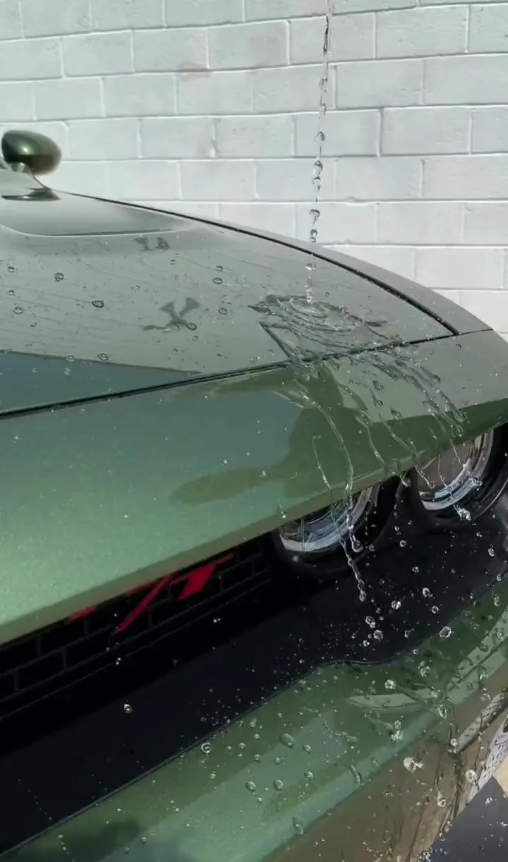 Water running off the hood of a green Dodge Challenger