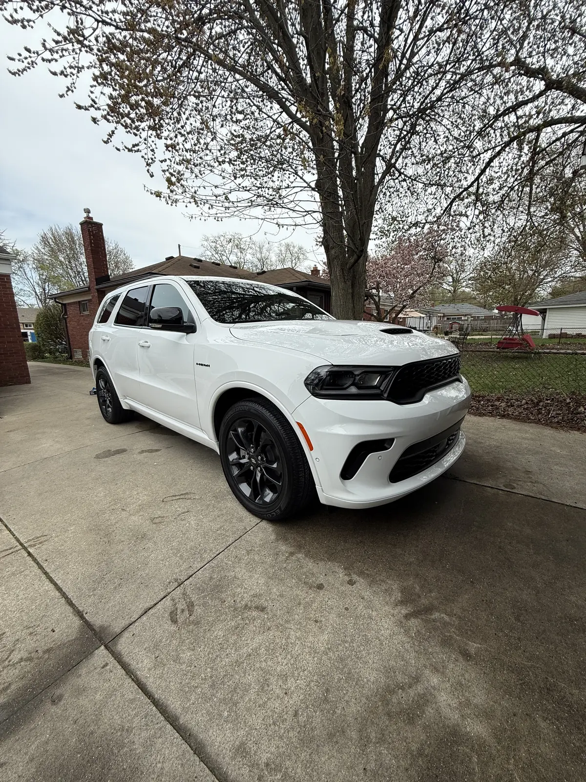 White Dodge Durango with black wheels parked beside a brick house