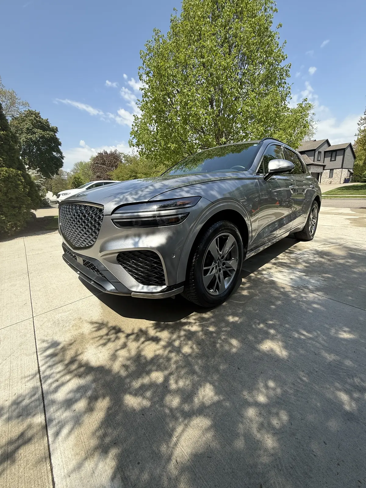 Grey Genesis GV70 in a tree-lined driveway
