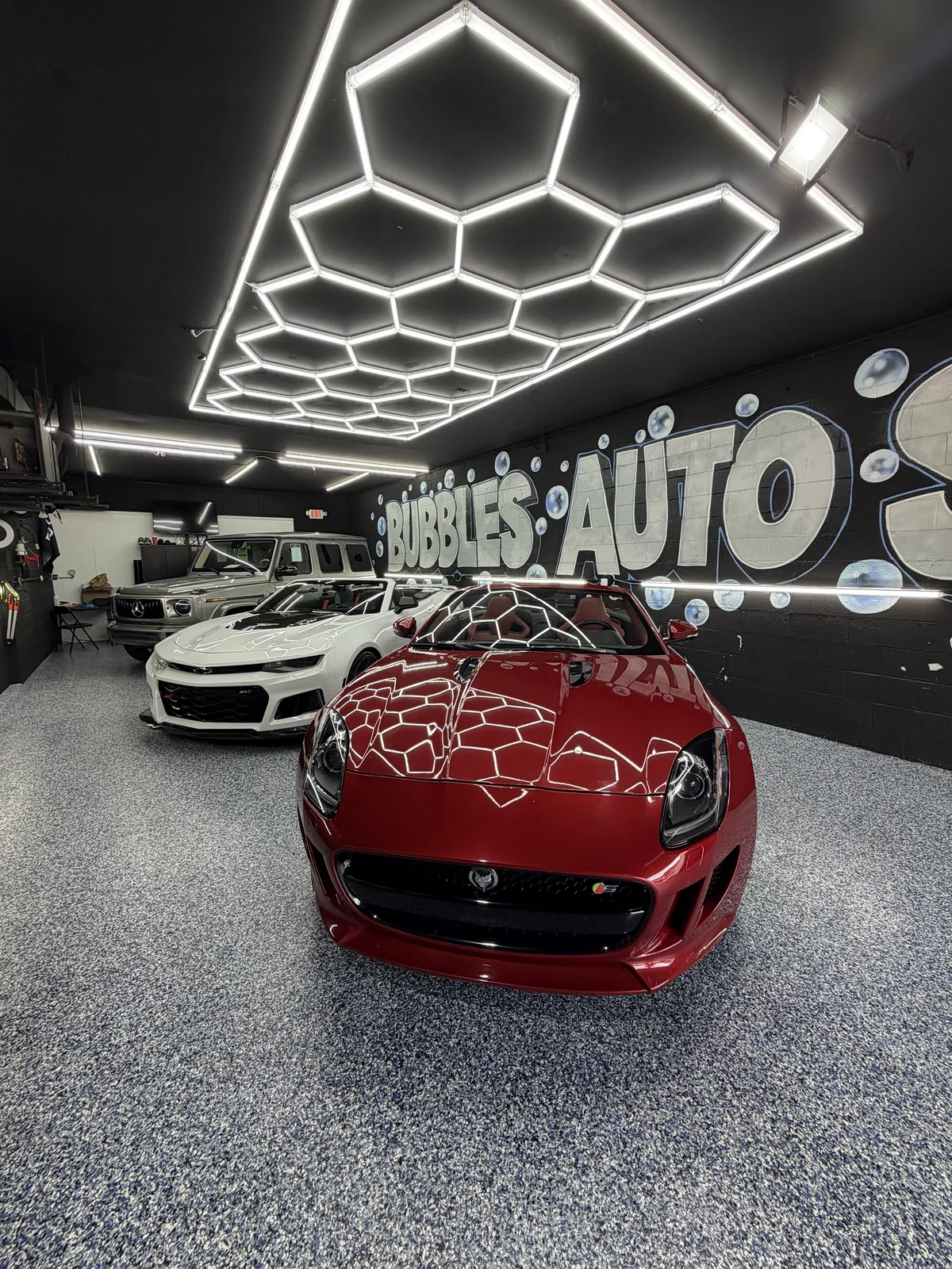 Red sports coupe under the hexagonal lights in the studio
