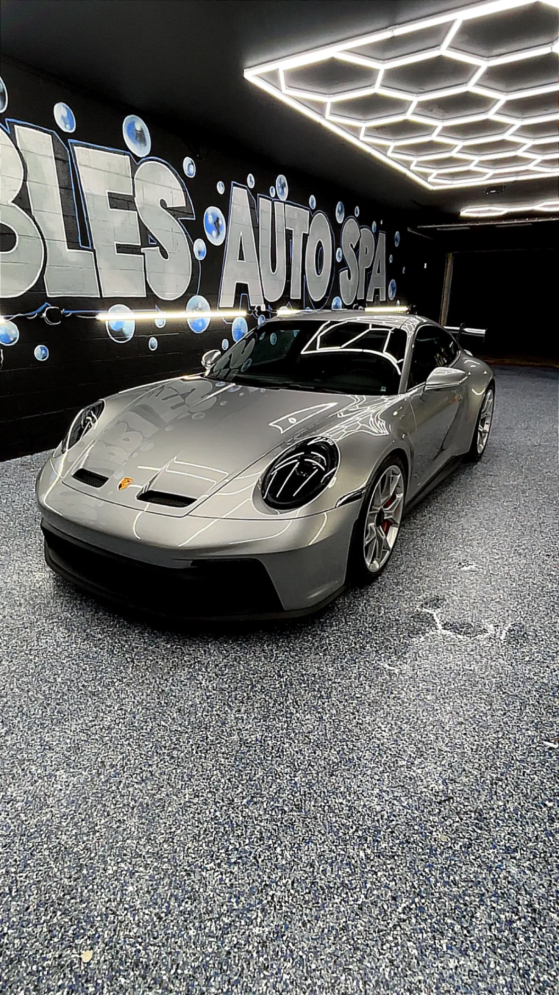 Porsche 911 GT3 under the hexagonal lights inside the Bubbles Auto Spa studio in St. Clair Shores