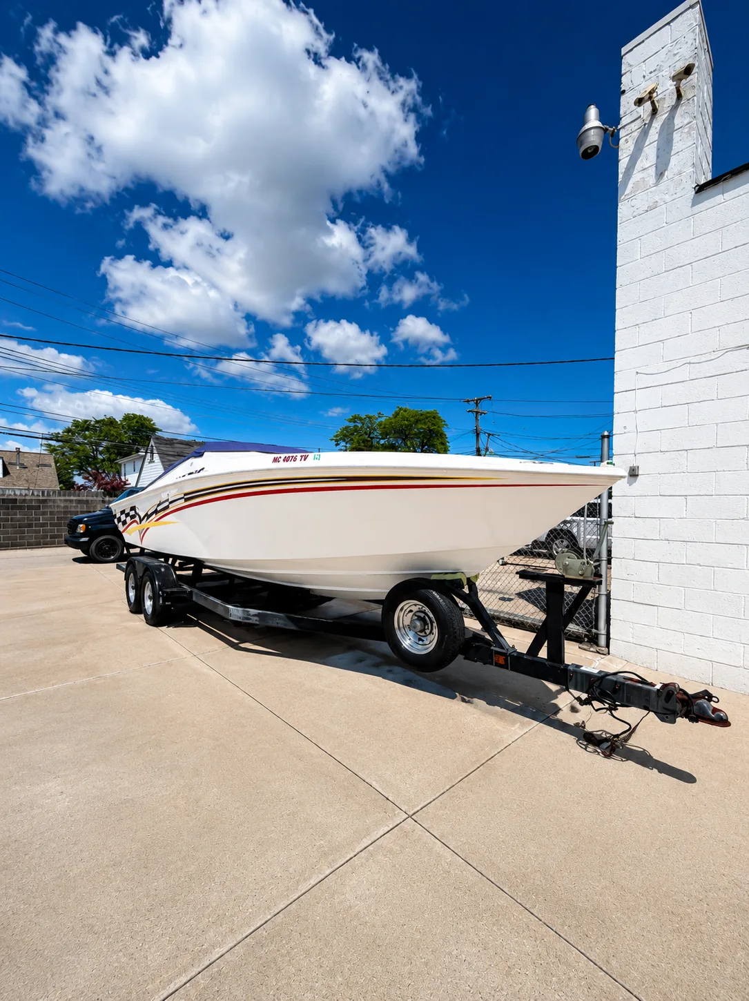 White speedboat with red stripes on a trailer outside the shop