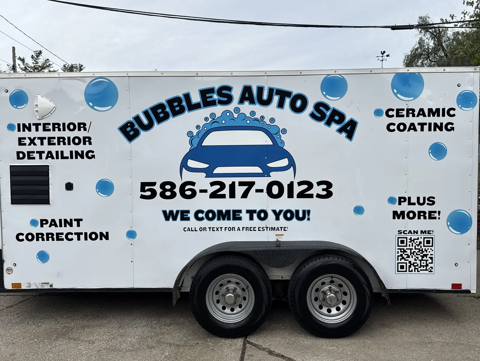 The white Bubbles Auto Spa trailer lettered with the phone number and We Come To You, parked on a driveway