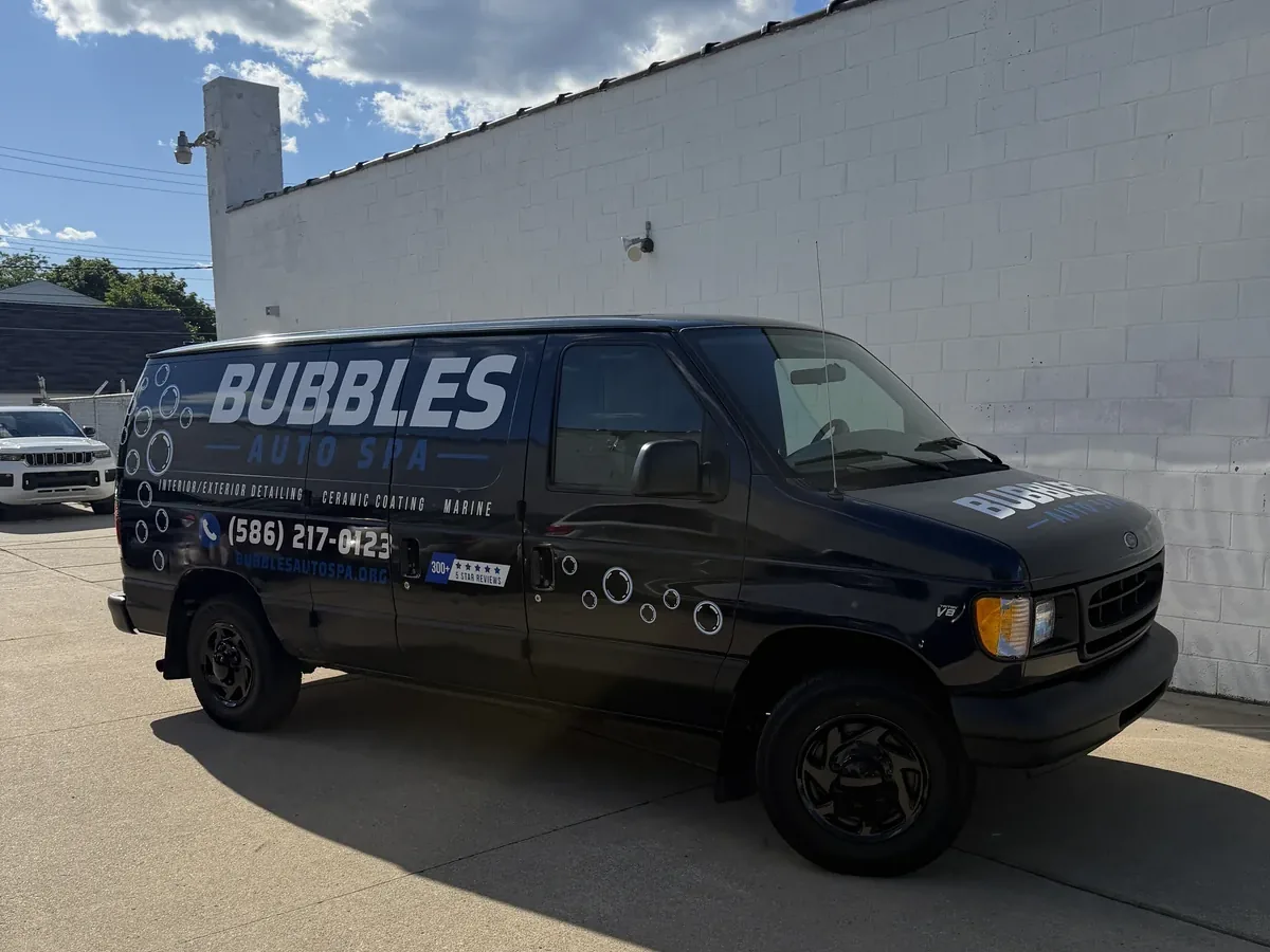 The black Bubbles Auto Spa van, lettered with the name and phone number, parked outside the shop